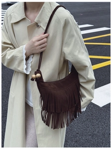 Detail of dark brown suede hobo bag featuring layered long tassels and wooden beads