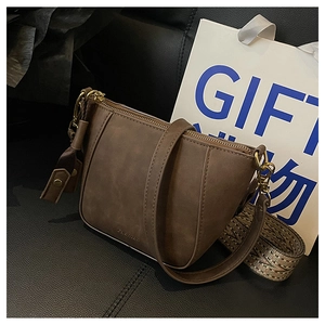 Detail of brown faux leather crossbody bag with gold zipper and Fashion logo stamp