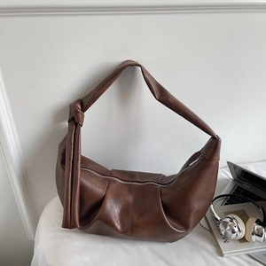 Detail of soft brown PU leather shoulder bag with pleated texture and stylish knot strap