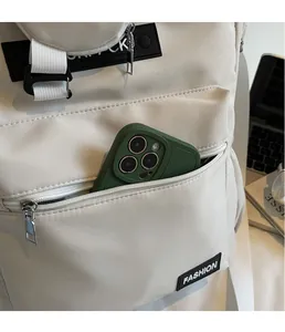 Vue détaillée de la poche avant zippée d'un sac d'école en toile beige avec rangement mobile