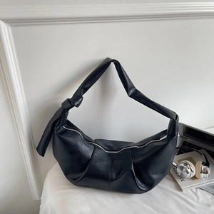Detail view of black crescent hobo bag with soft pleated leather and knot strap detail