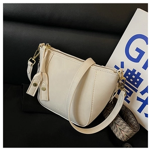 Close-up of white shell bag with golden hardware and ethnic patterned wide shoulder strap