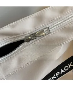 Détail de la fermeture éclair en métal argenté et de la toile blanche sur un sac à dos