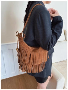 Detail view of brown suede hobo bag with long fringes and wooden bead drawstring accents