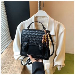 Dettaglio dello zaino in pelle intrecciata nera con fibbie vintage e perline colorate