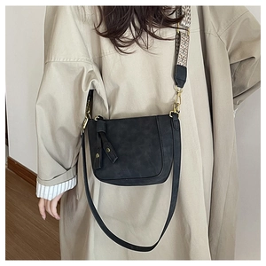 Close-up of black crossbody bag with ethnic style wide strap and golden hardware