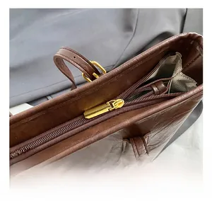 Detail shot of the golden zipper closure and vintage leather texture on brown tote bag