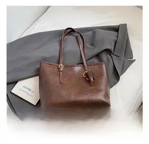 Close-up of brown vintage tote bag with oil-wax texture and cute elephant charm