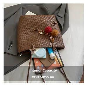 Macro shot of large capacity interior for woven tote bag with gadgets and plush charm