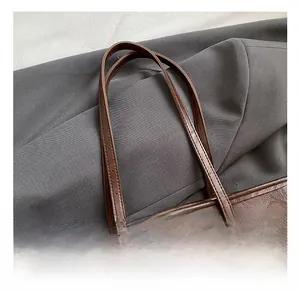 Detail of dark brown vintage faux leather tote bag with handle and animal pendant