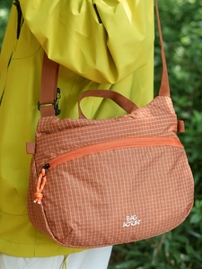 Bright orange crossbody bag with white grid pattern and adjustable strap for outdoor travel