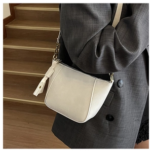 Detailed macro view of the cream leather shell bag with elegant gold chain and hardware
