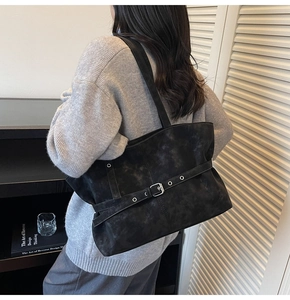 Detail of black suede tote bag featuring adjustable buckle strap and matte texture finish
