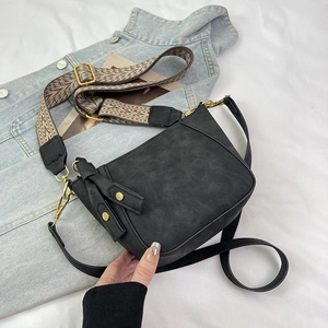 Detail of black leather crossbody bag with ethnic style wide strap and gold hardware