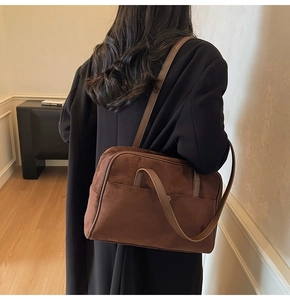 Detail of vintage brown suede shoulder bag with retro piping and spacious front pocket