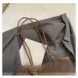 Detailed macro view of retro brown hand-woven tote bag texture and leather strap