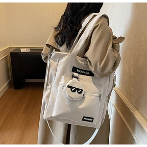 Détail du sac cabas beige avec poignée fonctionnelle et pendentif lunettes de soleil