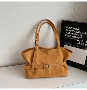 Detail of a ginger yellow faux leather tote bag with stylish buckle strap and soft texture