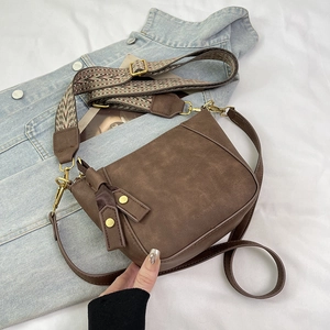 Detail of vintage brown shell bag with wide geometric woven strap on denim background
