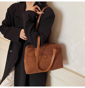 Detail of vintage brown suede bowling bag featuring a front pocket and long handles