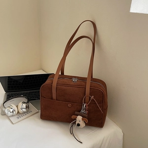 Detail of deep brown suede bowling bag with shoulder straps and plush puppy charm