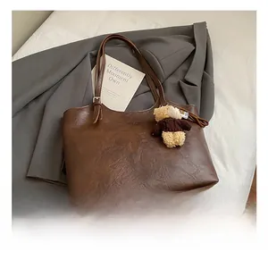 Detail view of large brown vintage tote bag with textured faux leather and bear charm
