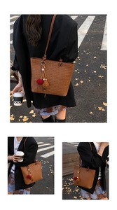 Detail of a brown woven tote bag with fuzzy charms on a city street background