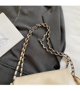 Detailed close-up of the woven chain strap on a cream-colored leather tote bag