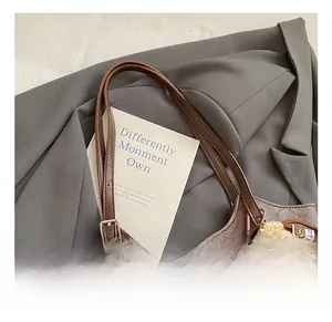 Close-up of brown textured leather tote bag with logo and teddy bear charm detail
