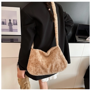 Detail of soft camel plush bucket bag worn on shoulder over a black blazer jacket