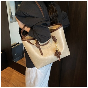 Close-up of beige leather tote bag with brown edge detail and elephant charm