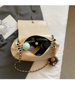 Spacious interior of beige chain shoulder bag with cosmetics and plush charm detail