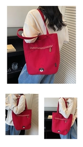 Détail d'un sac cabas en toile rouge avec surpiqûres en zigzag et broderie tête de chien