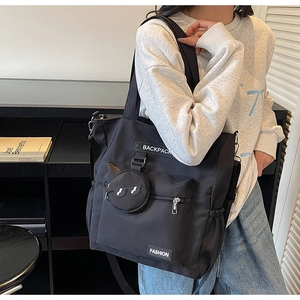 Vue détaillée du sac cabas en toile noire avec poches zippées et porte-monnaie suspendu