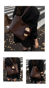 Detail of dark brown matte leather tote bag with a cute bear charm on autumn street