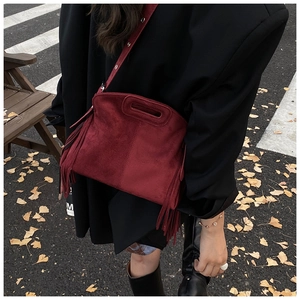 Detail of burgundy fringe crossbody bag on ginkgo leaves background with autumn vibe