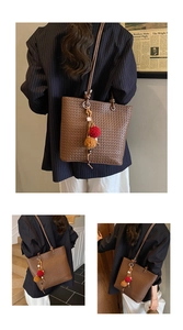 Detailed view of dark brown woven tote bag featuring decorative plush charm tassels