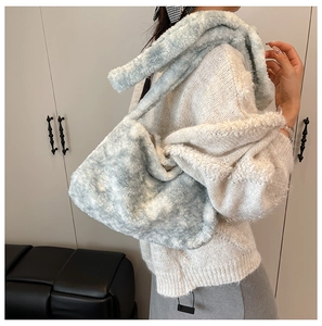Detail of light blue faux fur bucket bag worn on shoulder over a white sweater