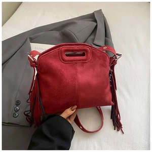 Close-up of red suede tote with long side tassels and minimalist cutout handle details