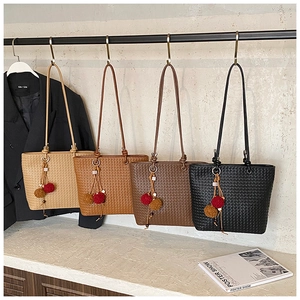 Detail of four woven tote bags in beige, caramel, brown, and black with tassel charms