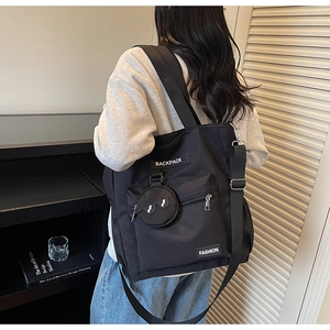Détail du sac cabas en nylon noir porté par le mannequin montrant sa grande capacité