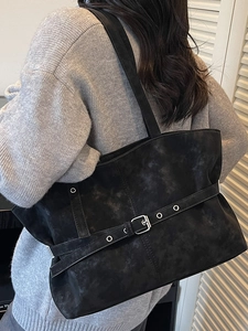Minimalist black tote bag with strap buckle detail and matte marble texture finish