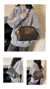 Close-up of black leather shoulder bag with dark metal chain and plush monster charm