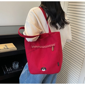 Détail du sac fourre-tout en toile rouge avec broderie de chiot et coutures en zigzag