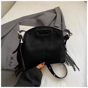 Detail view of a black suede tassel bag with oval cutout handle and silver metal hardware