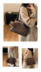 Detail of dark brown faux leather shoulder bag with gold logo and plush charm accessory
