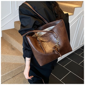 Close-up of vintage brown leather tote bag showing glossy texture and shoulder straps