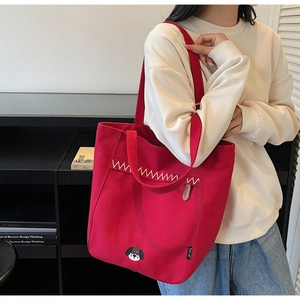 Détail du sac cabas en toile rouge avec broderie chien et coutures en zigzag