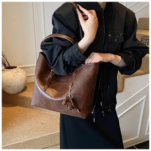 Brown leather tote bag with tassel charm shown as a stylish shoulder bag for daily commute