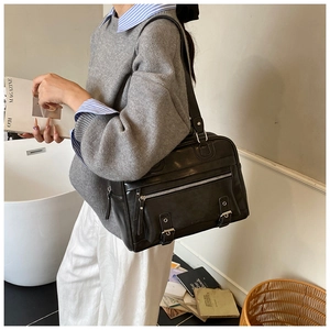 Detail view of large black retro tote bag with functional zippers and vintage buckles